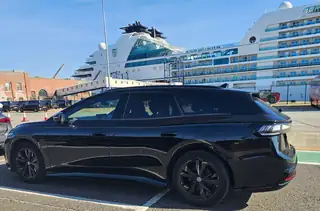 Leo Taxis black estate taxi parked at a cruise port beside a cruise ship